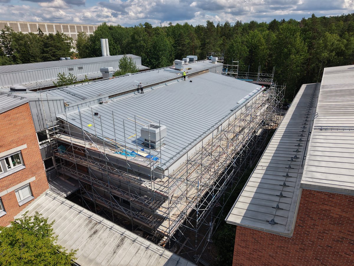 Flygbild över AIR27:s takarbeten med plåttak, installationer och byggställningar mellan laboratoriebyggnaderna.